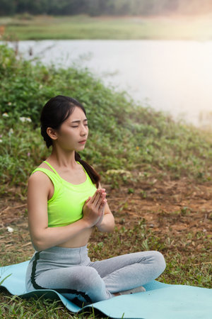 Young asian woman in sportswear meditating on yoga matの写真素材