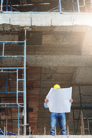 Engineer with blueprint in building construction site