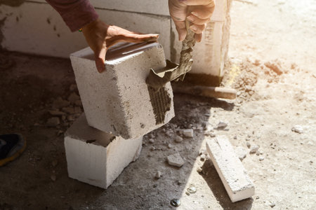 Bricklayer plastering cement on brick. Mason worker building exterior walls.の写真素材