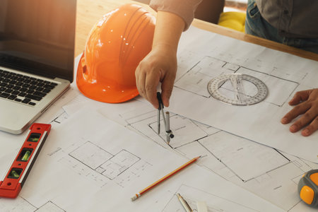 An architect or engineer working on blueprint, An architect or engineer uses a divider gauge on the...