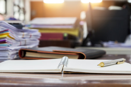 A pen on notebook with Documents in office;