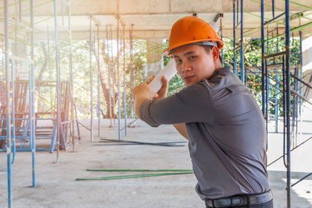 The architect relaxes by acting as a baseball player. Engineer with blueprint in building construction siteの写真素材