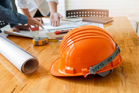 helmet on wooden desk with architect background