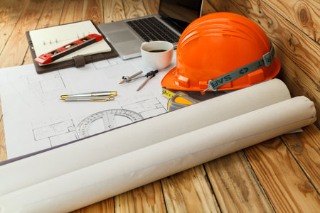 Helmet and measurement tool on blueprint, architectural concept