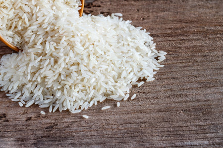 Uncooked dry rice in brown bowl on wooden tableの写真素材