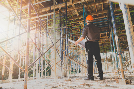 Engineer with blueprint in building construction site