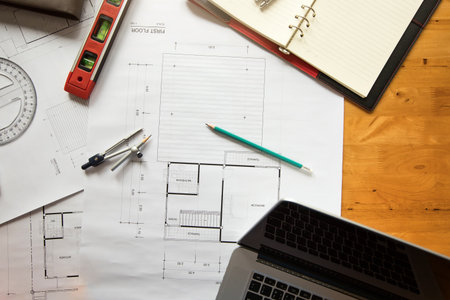 Top view of measurement tool with helmet and laptop on blueprint, architectural concept