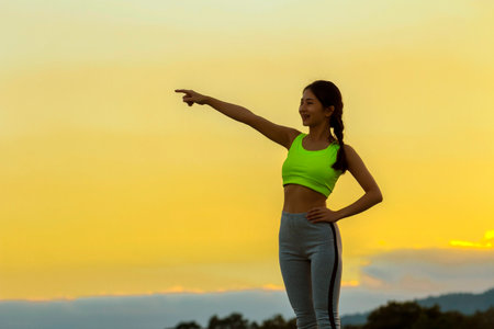 Young asian woman in sportswear pointing at the mountainの写真素材