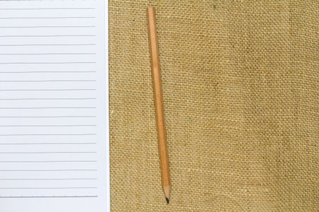 Notebook and pencil on canvas textile, top view shotの写真素材