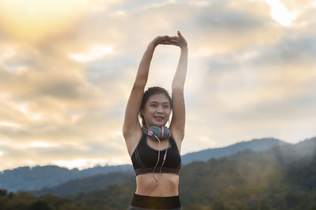 Young asian woman runner raise her hand up to resting after workout sessionの写真素材