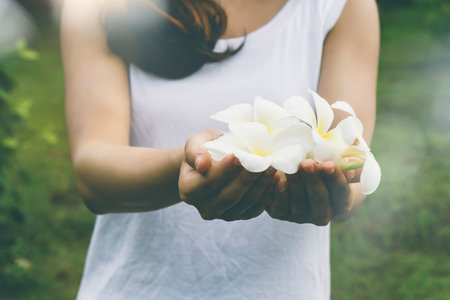 Beautiful young asian woman holding a white flowers in park, vitage effectの写真素材