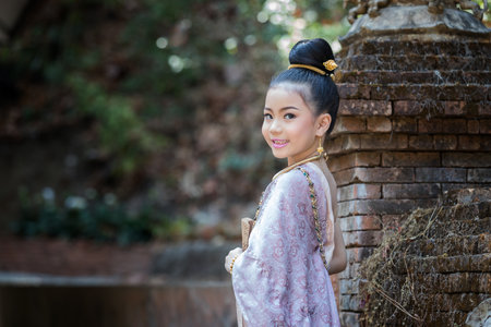 Closeup shot of cute Thai girl wearing thai traditional clothing. She turned to look at camera and smileの写真素材