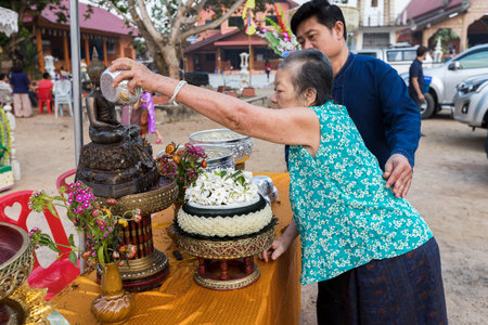 April 15, 2018 - Chiang mai, Thailand: Thai old woman and her son are bathing the Statue of Buddha in the Thai Songkran Festival.のeditorial素材