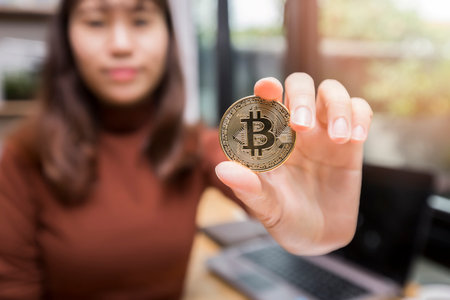 Golden bitcoin (cryptocurrency) in hand of businesswoman. New Virtual money concept