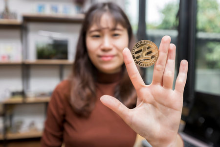 Golden Litecoin (cryptocurrency) in hand of businesswoman. New Virtual money conceptの写真素材
