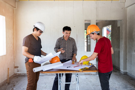 Engineer and architect discussing with foreman about project in building construction siteの写真素材