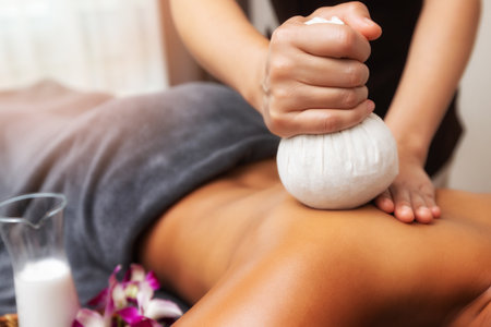 Masseur doing back massage with compress in spa salon. Beauty treatment concept.の写真素材