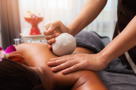 Masseur doing back massage with compress in spa salon. Beauty treatment concept.の写真素材