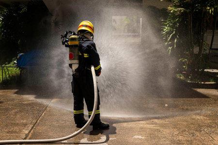 Firefighters with extinguisher spraying high pressure water to fighting the fire flame in an emergency situation.の写真素材