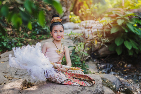 Cute Thai girl wearing thai traditional clothing with feather fan.の写真素材