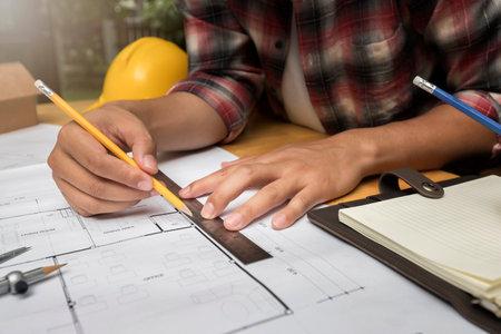 Architect measuring scale on blueprint in construction site