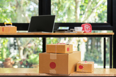 Cardboard parcel box and laptop ondesk at workplace of startup small business owner for online selling.の写真素材