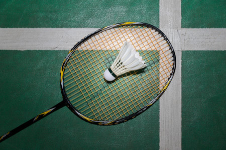 Top view of white badminton shuttlecock and racquet on wooden floor.の写真素材