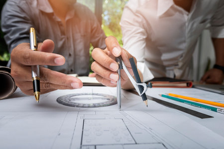 Engineer or architect meeting for project working with partner and using divider compass tools on...