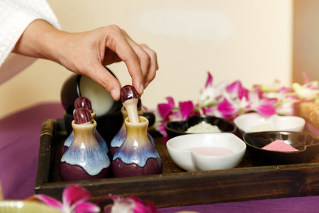 Woman open the essential oil bottle with skin care products. Sea salt, essential oil and treatment body scrubs in basket.の写真素材