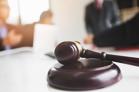 Wooden gavel on table in lawyer's office. Lawyer having team meeting with the client. Concepts of...