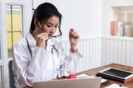 Female medic taking her glasses off to rest her eyes and relax from work.の写真素材