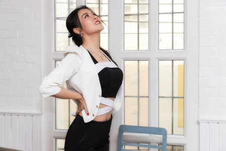 Office syndrome concept. Businesswoman twisting the body to relieve fatigue, suffering from pain after sedentary working in incorrect posture.の写真素材