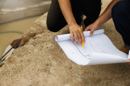 Team of construction workers discussing project details with blueprint in construction site.