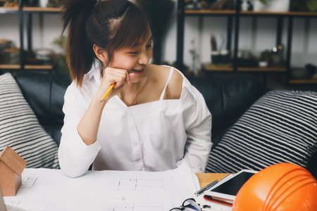 Female architect working on blueprint architects project in office.の写真素材