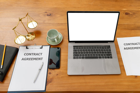 Laptop, contract documents and brass balance scale on the lawyer's desk.