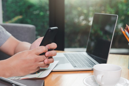 A man holding a smartphone in one corner of the home office.の写真素材