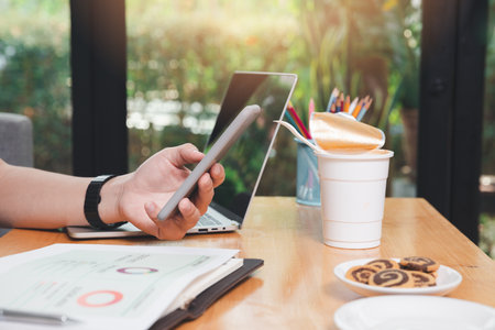 A man in casual wear using phone and working at home office.