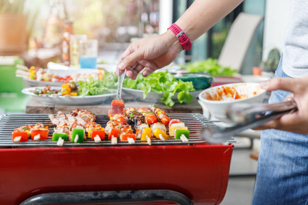 A man grilling pork and barbecue in dinner party. Food, people and family time concept.の写真素材