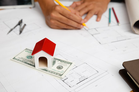 House model on dollar banknote and blueprint with architecrt in office. Real estate concept. Home...
