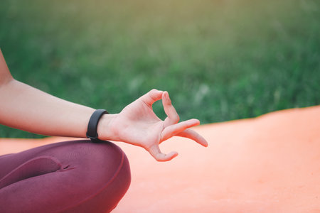 Asian woman practicing yoga in Root Bond, Mula Bandha pose on the mat in outdoor park.の写真素材
