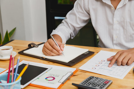 Businessman take a note on notebook with documents in home office.