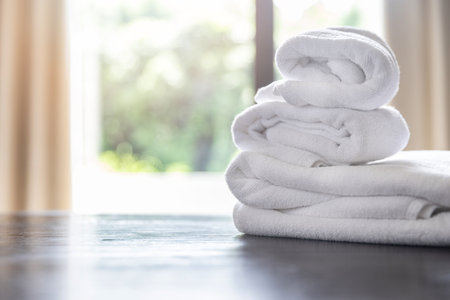 Roll up of white towels on table with copy space on blurred room background. For product display montage.の写真素材