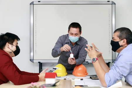 Confident team of architect and engineer wearing protective masks working together in a office....