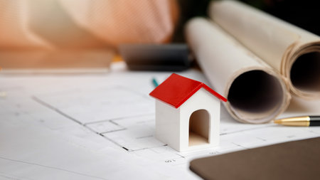 House model on desk over architect working with blueprint in a office. Architectural concept.の写真素材