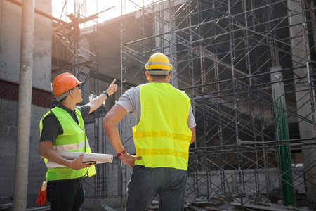 Engineer discussing with foreman about project in building construction site.