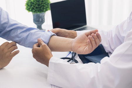 The doctor rolls up the patient's sleeve to measure blood pressure or give an injection.の写真素材