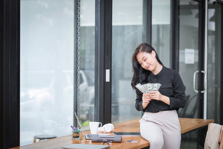 Beautiful young woman holding us dollar money. business, finance, saving, banking and online shopping concept.の写真素材