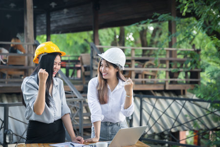 Two asian female architects clenched their fists and shouted YEAH!! Glad to know that the client likes their work and agrees to sign a contract. Successful project.の写真素材