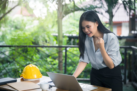 Asian female architects clenched her fist and shouted YEAH!! Glad to know that the client likes her work and agrees to sign a contract. Successful project.の写真素材