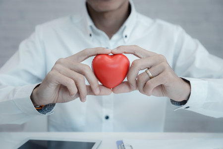 Doctor hands hold a red heart over desk. Concept of health care and medical.の写真素材